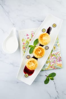 lush and tall cheesecakes with jam and mint on a white plate