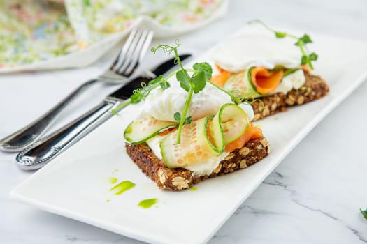 canapes on black bread with cheese, red fish, herbs and cucumber