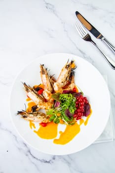 cooked shrimp with herbs and berries on a white plate