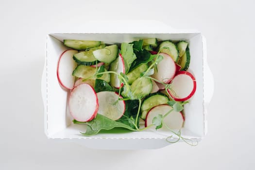 salad of radishes, herbs and cucumbers in a white container