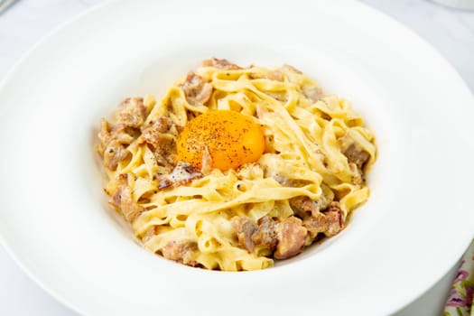 pasta in cream sauce with egg and black pepper on top