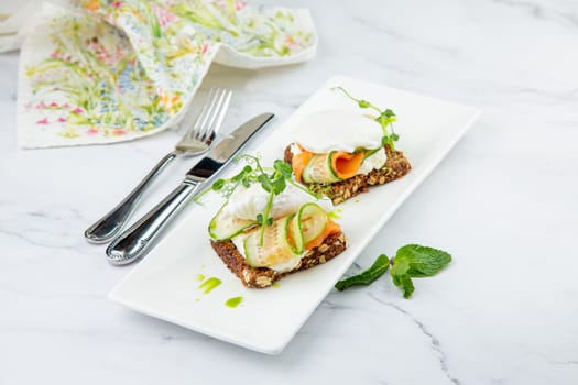 canapes on black bread with cheese, red fish, herbs and cucumber