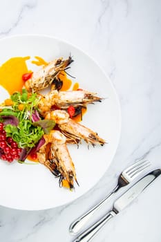 cooked shrimp with herbs and berries on a white plate