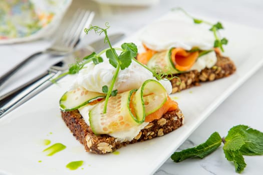 canapes on black bread with cheese, red fish, herbs and cucumber