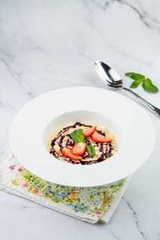 porridge with strawberries, mint and berry jam in a white plate