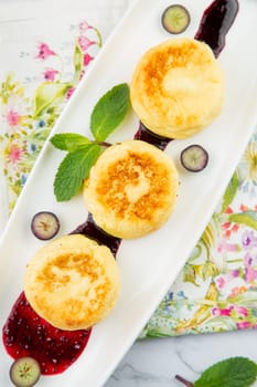 lush and tall cheesecakes with jam and mint on a white plate