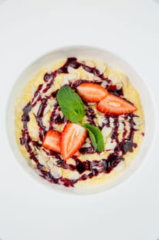 porridge with strawberries, mint and berry jam in a white plate