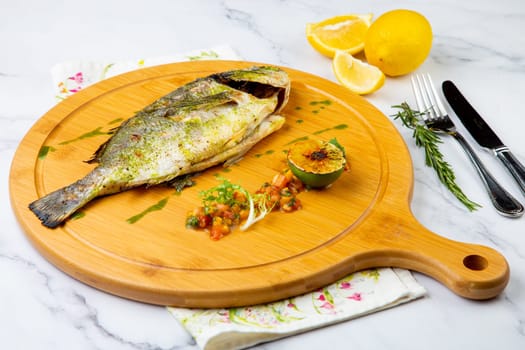 baked fish with spices and lemon on a wooden tray