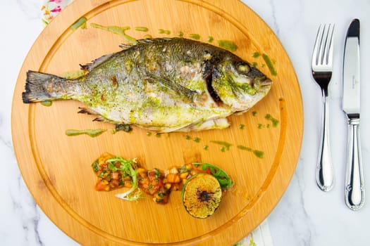 baked fish with spices and lemon on a wooden tray