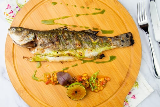 baked fish with spices and lemon on a wooden tray