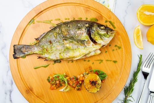 baked fish with spices and lemon on a wooden tray