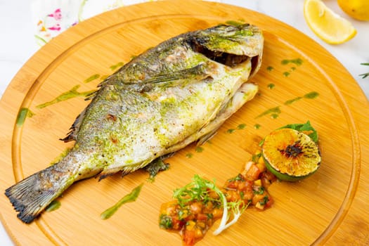 baked fish with spices and lemon on a wooden tray