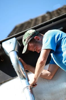 Roofer repairs a downspout