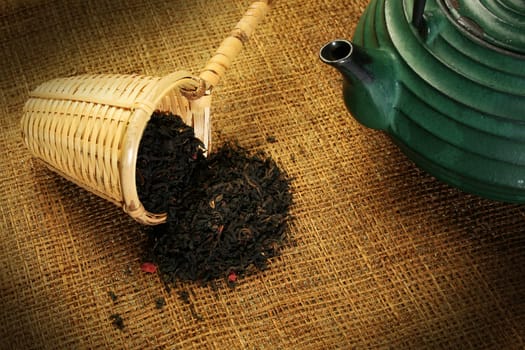 Chinese teapot and a wicker scoop with herb tea leaves