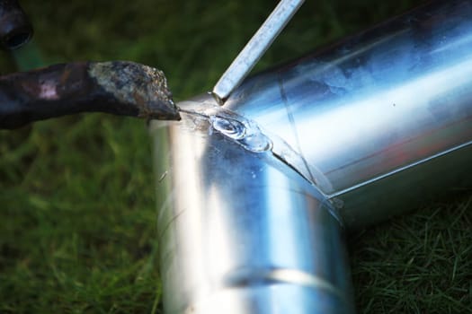 Roofer welds a downpipe for the house