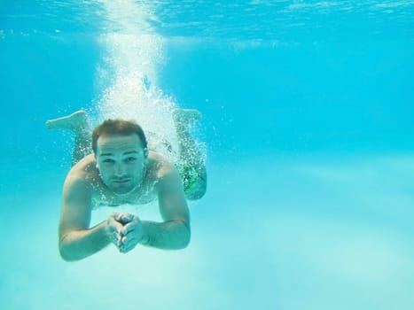 Man swimming under water in pool