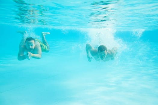 Two men swimming together under water in