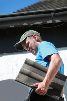 A roofer replaces tiles