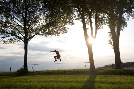 young man on the slackline in sunset