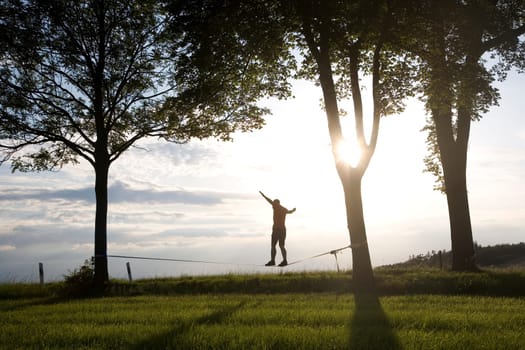 young man on the slackline in sunset