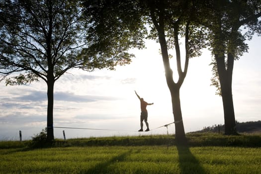 young man on the slackline in sunset