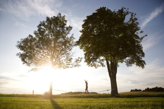 young man on the slackline in sunset