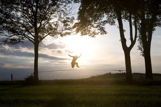 young man on the slackline in sunset