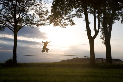 young man on the slackline in sunset