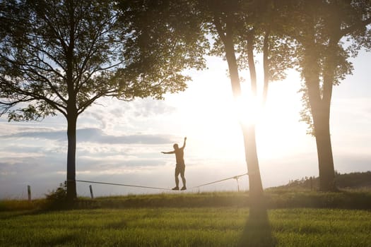 young man on the slackline in sunset
