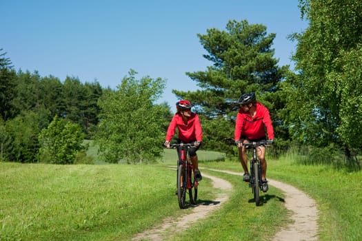 Summer - young man woman couple ride mountain bike in nature