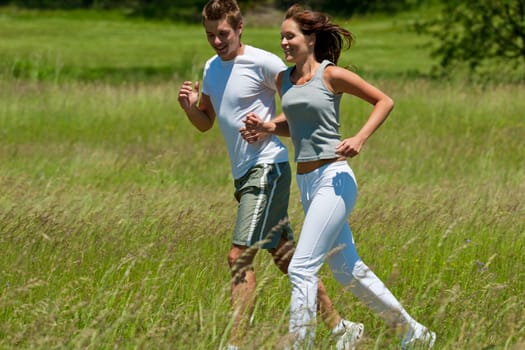 Young man and woman jogging in meadow