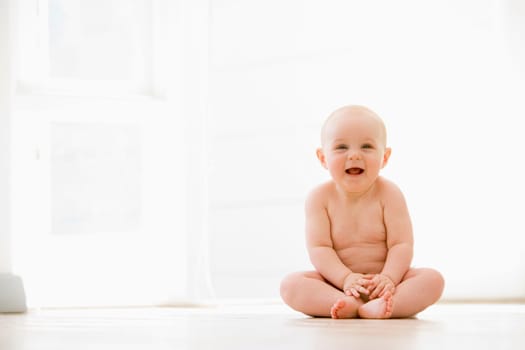 Baby sitting indoors smiling