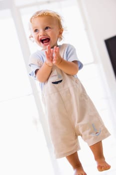 Young boy standing indoors applauding and smiling