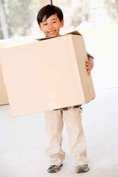 Young boy with box in new home smiling