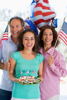Family outdoors on fourth of July with flags and cookies smiling