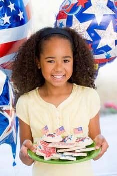 Young girl on fourth of July with balloons and cookies smiling