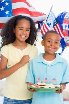 Brother and sister on fourth of July with flag and cookies smiling