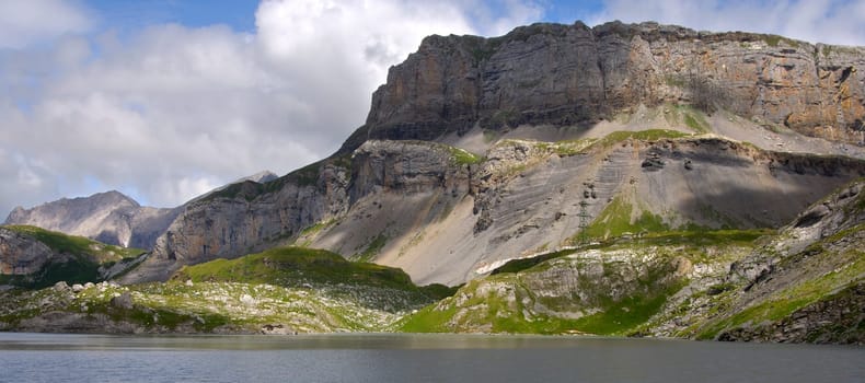 Lake at the foot of a steeply rising,heavily weathered alpine massif,A