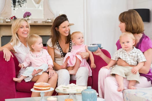 Three mothers in living room with babies and coffee smiling