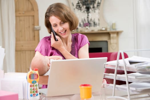Mother and baby in home office with laptop and telephone