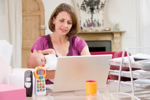 Mother and baby in home office with laptop