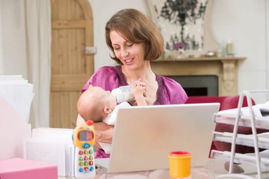 Mother and baby in home office with laptop