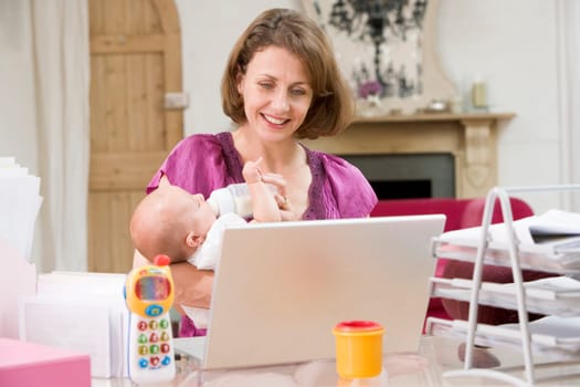 Mother and baby in home office with laptop