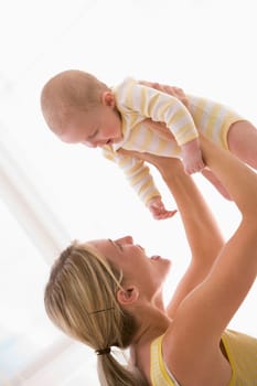 Mother holding baby indoors smiling
