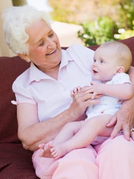 Grandmother outdoors on patio with baby smiling