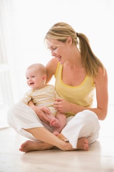 Mother and baby sitting indoors smiling
