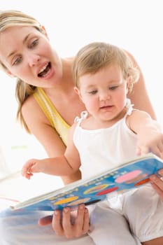Mother and baby reading book indoors and pointing