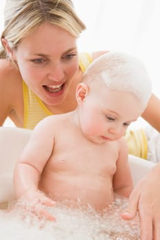 Mother giving baby bubble bath smiling