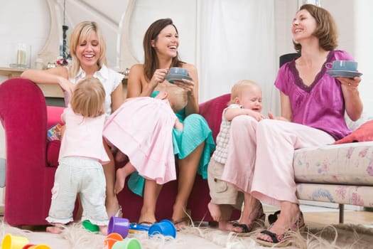 Three mothers in living room with coffee and babies smiling