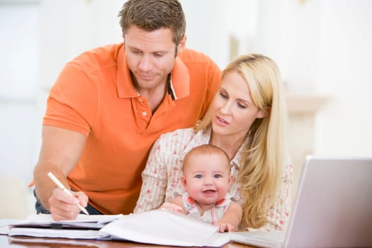 Couple and baby in dining room with laptop